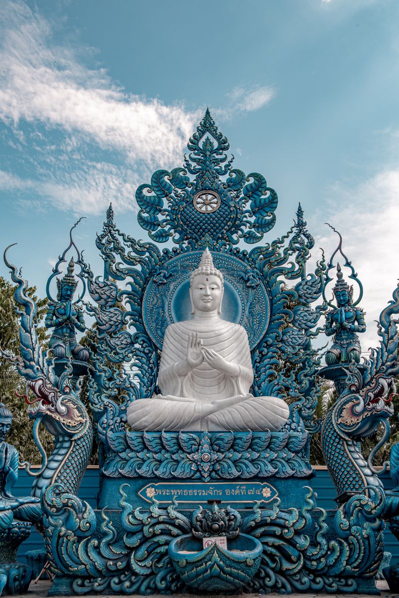 Buda blanco sentado en el interior azul y dorado del Templo Azul de Chiang Rai