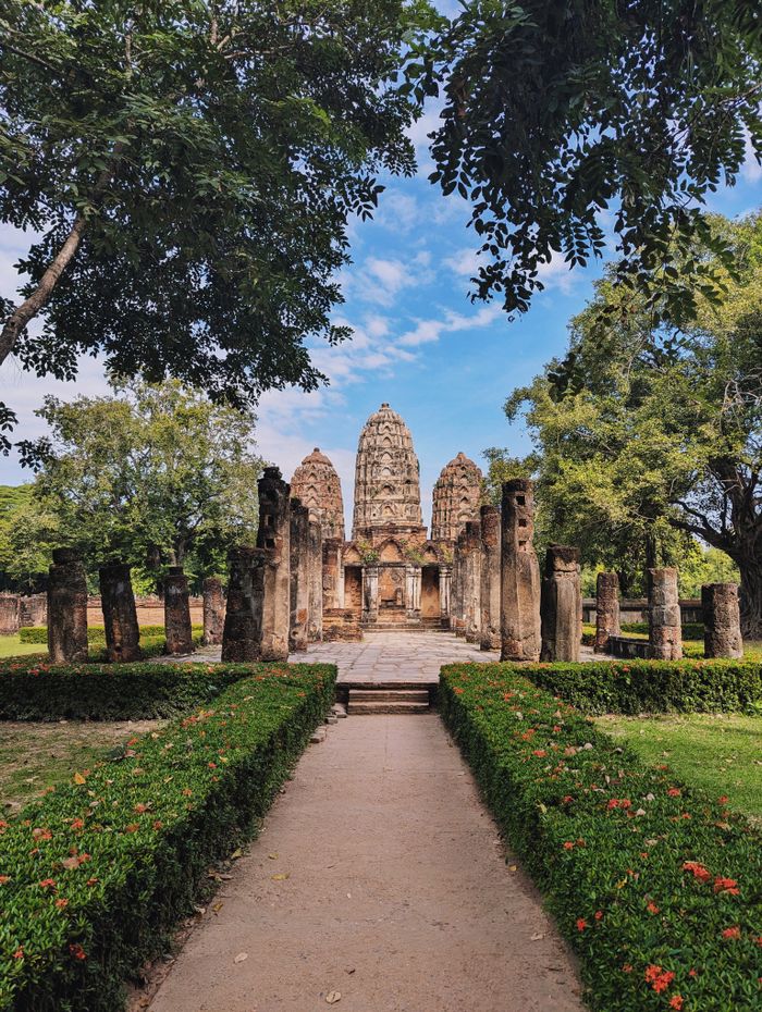 Camino arbolado entre las ruinas del parque hist&oacute;rico de Sukhothai